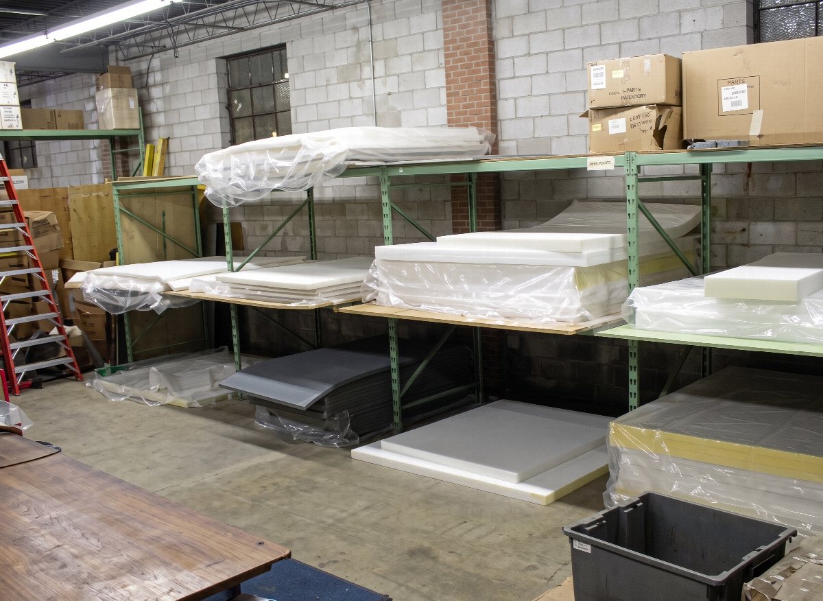 Sheets and blocks of foam rubber stacked on warehouse racking in the Hull Street Outlet foam department.