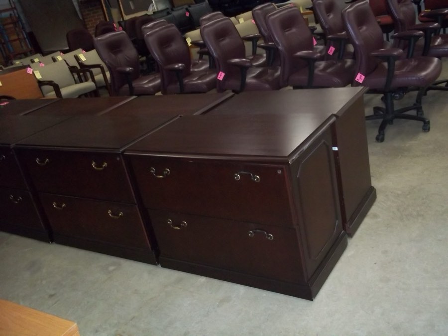 A used dark wood executive desk with a double pedestal and brass drawer pulls.