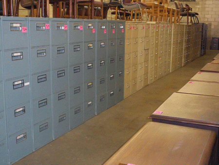 Rows of used grey vertical file cabinets lined against a wall.