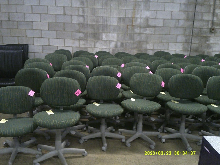 Rows of used secretarial task chairs with green and black upholstery.