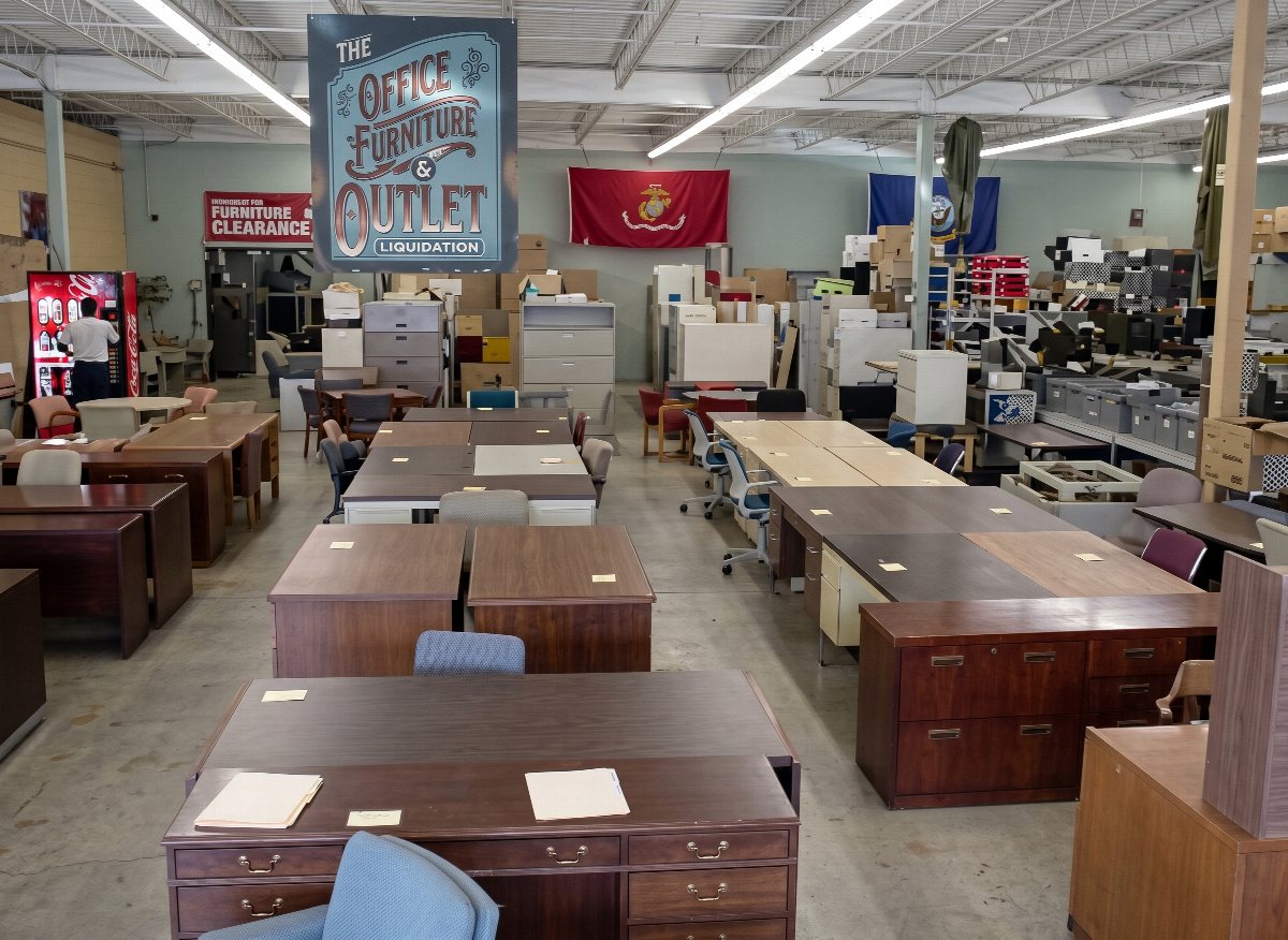 The office furniture floor at Hull Street Outlet, with rows of desks, chairs and file cabinets under a hanging Office Furniture Outlet sign.