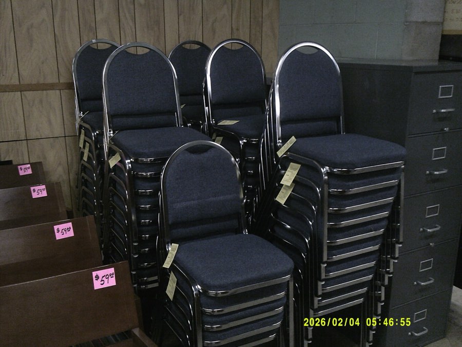 Stacks of used blue upholstered stacking chairs on the warehouse floor.