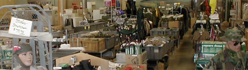 A wide aisle of the Hull Street Outlet warehouse stacked with bins, camp furniture and boxed goods.