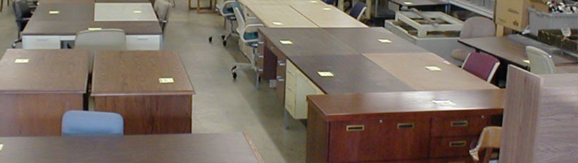 The used office furniture floor at Hull Street Outlet, filled with wood and laminate desks, chairs and file cabinets.